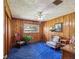 Cozy bedroom with wooden walls, plush blue carpet, and comfortable seating at 6823 Oak Hill Dr, New Port Richey, FL 34653