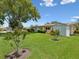 Single-story home with a well-manicured lawn, colorful landscaping, and a detached shed at 6823 Oak Hill Dr, New Port Richey, FL 34653