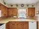 Vintage kitchen featuring warm wood cabinets, patterned wallpaper, and modern appliances, offering a cozy and functional space at 6823 Oak Hill Dr, New Port Richey, FL 34653