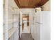 View into an adjacent kitchen from a bright storage area featuring white appliances and open shelving at 6823 Oak Hill Dr, New Port Richey, FL 34653