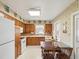 Eat-in kitchen featuring vintage wallpaper, wooden cabinets, and white appliances, capturing a cozy, nostalgic ambiance at 6823 Oak Hill Dr, New Port Richey, FL 34653