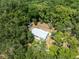 Aerial view showcases a home with additional living quarters surrounded by lush trees at 7340 20Th, Zephyrhills, FL 33540