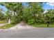 Long driveway leading to a charming home, lined with lush greenery and mature trees at 7340 20Th, Zephyrhills, FL 33540