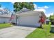 View of garage with a driveway and landscaping with mulch and plants at 7736 Chadwick Dr, New Port Richey, FL 34654