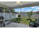 View of fenced backyard and green grass with a ceiling fan from the tiled screened patio at 7736 Chadwick Dr, New Port Richey, FL 34654
