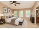 Bright bedroom with a ceiling fan, beige walls, a large rug, and three windows at 8409 Blue Rock Dr, New Port Richey, FL 34653