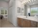 Bright bathroom featuring a single sink vanity, large mirror, and a glimpse into the adjacent bedroom at 9019 Flagstick Ln, Hudson, FL 34667