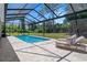 Screened pool with patio lounge chairs and view of back yard at 9019 Flagstick Ln, Hudson, FL 34667