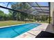 Relaxing screened-in pool area with seating overlooking a lush green yard, offering a serene escape at 9019 Flagstick Ln, Hudson, FL 34667