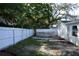 Backyard with above-ground pool, white fence, mature trees, and grass and sandy areas at 9116 Gray Fox Ln, Port Richey, FL 34668