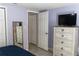 Bedroom with chest of drawers, mirror and TV, featuring a neutral palette and tiled floors at 9116 Gray Fox Ln, Port Richey, FL 34668