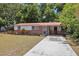 Attractive single-story home with a red metal roof, well-manicured lawn, and a convenient long driveway at 9306 21St, Tampa, FL 33612