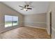 Cozy bedroom with wood floors, ceiling fan, large window, and neutral paint at 9729 Bay Colony Dr, Riverview, FL 33578
