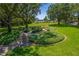 A beautifully landscaped common area with benches, manicured shrubs, and walking paths at 9729 Bay Colony Dr, Riverview, FL 33578