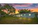 The backyard featuring a screened patio at sunset at 9744 Rainelle Ln, Port Richey, FL 34668