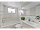 Bright bathroom featuring a shower-tub combo, tiled walls, and a classic sink at 9744 Rainelle Ln, Port Richey, FL 34668