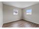 A cozy bedroom with wood floors, neutral walls, and plenty of natural light from two windows at 9744 Rainelle Ln, Port Richey, FL 34668