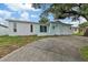 Charming light blue home featuring a garage and quaint doorway beneath a large tree at 9744 Rainelle Ln, Port Richey, FL 34668
