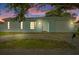 Charming light blue home with a garage door and inviting front entrance at twilight at 9744 Rainelle Ln, Port Richey, FL 34668