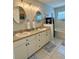 Well-lit bathroom with double sinks, decorative mirrors, tiled floors, and a relaxing soaking tub at 9808 Riverchase Dr, New Port Richey, FL 34655