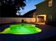 Night view of the backyard pool with vibrant green lighting, perfect for evening swims and outdoor entertainment at 9808 Riverchase Dr, New Port Richey, FL 34655