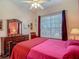 Cozy bedroom featuring a ceiling fan, a large window, and an ornate wooden dresser with a mirror at 10181 Holly Berry Dr, Weeki Wachee, FL 34613
