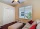 Cozy bedroom featuring dark hardwood flooring, neutral walls, double closet, and a comfortable sofa and ottoman at 10181 Holly Berry Dr, Weeki Wachee, FL 34613