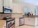 Kitchen with stainless steel appliances, white cabinets, and view of window and plants at 10181 Holly Berry Dr, Weeki Wachee, FL 34613
