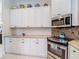 Well-lit kitchen boasting ample storage, white cabinetry, and stainless steel oven and microwave at 10181 Holly Berry Dr, Weeki Wachee, FL 34613