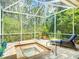 Enclosed lanai with spa, lounge chair, and lush backyard views beyond the screens at 10181 Holly Berry Dr, Weeki Wachee, FL 34613