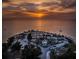 An aerial view shows a sandy beach with a pavilion, palm trees, and cars under a sky with a colorful sunset at 111 E Cedar St, Tarpon Springs, FL 34689