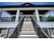 Inviting entrance with grand staircase, featuring black metal railings, leading to a welcoming porch at 111 E Cedar St, Tarpon Springs, FL 34689