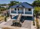 Two-story home showcasing its metal roof, double staircases, and ground floor parking, nestled among lush trees at 111 E Cedar St, Tarpon Springs, FL 34689