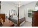 Cozy bedroom with a four-poster bed, ceiling fan, and natural light from the window at 11398 Juglans Dr, Odessa, FL 33556