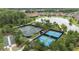 Aerial view features tennis and pickleball courts surrounded by trees near a picturesque lake at 11398 Juglans Dr, Odessa, FL 33556