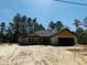 An exterior view of a single-Gathering home, revealing its block construction, dark roof, and garage in a natural setting at 11406 Labrador Duck Rd, Weeki Wachee, FL 34614