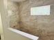Modern shower with sleek, horizontal tile and glass shelf for storage and natural light from the window at 11406 Labrador Duck Rd, Weeki Wachee, FL 34614
