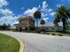Community center exterior with mature landscaping, palm trees, and circular drive under a partly cloudy sky at 11619 Boynton Ln, New Port Richey, FL 34654