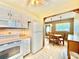 Efficient kitchen layout connecting to the dining area and featuring white appliances and cabinetry at 11619 Boynton Ln, New Port Richey, FL 34654