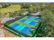 Aerial view of pristine blue and green pickleball courts surrounded by lush greenery at 11752 Wheatfield Loop, Hudson, FL 34667