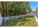 Well-maintained backyard with green grass, white fence, and view of mature trees at 12055 Colony Lakes Blvd, New Port Richey, FL 34654