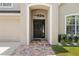 Inviting front entrance with a dark wood door, decorative brick walkway, and manicured landscaping at 12055 Colony Lakes Blvd, New Port Richey, FL 34654