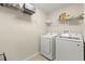 Functional laundry room with white washer and dryer, shelving, and neutral walls and tile floors at 12055 Colony Lakes Blvd, New Port Richey, FL 34654