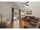 Open-concept living room with hardwood floors, ceiling fan, and glass sliding doors to the patio at 12055 Colony Lakes Blvd, New Port Richey, FL 34654