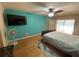 Bright bedroom featuring a blue accent wall, ceiling fan, and mounted television at 12090 Stoneville Ct, Spring Hill, FL 34609
