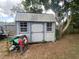 Exterior view of the wooden shed with a metal roof and two windows on a lot with a tree at 12090 Stoneville Ct, Spring Hill, FL 34609