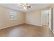 Bedroom with wood-look flooring, neutral walls, ceiling fan, and an open doorway leading to another room at 12155 Environmental Dr # 8, New Port Richey, FL 34654