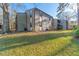 Exterior view of a multi-unit residential building with green lawn space and mature trees surrounding it at 12155 Environmental Dr # 8, New Port Richey, FL 34654