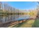 A tranquil pond surrounded by mature trees offers a serene backdrop, enhanced by a rustic wooden bench at 12155 Environmental Dr # 8, New Port Richey, FL 34654