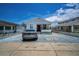 Wide view of a quaint, white-bricked home with a long driveway and well-kept front yard at 124 Athens St, Tarpon Springs, FL 34689